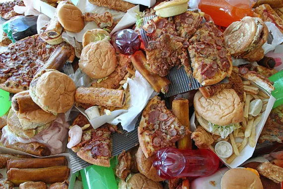 Pile of ultra-processed foods like burgers and pizza containing trans fat.