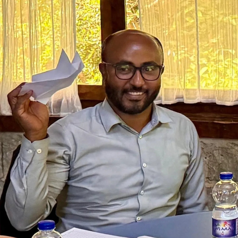 An African man doing a team exercise, holding up an origami model