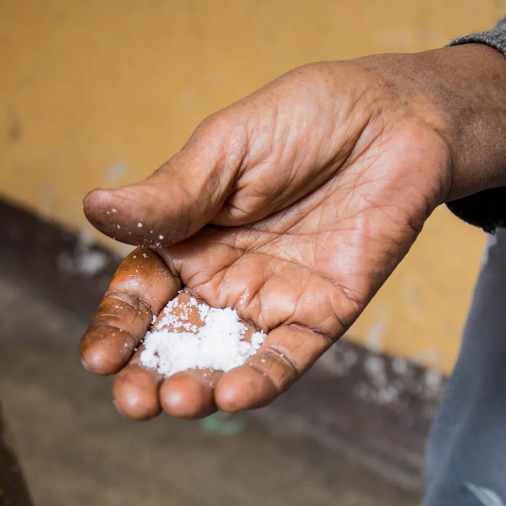 An elderly African ladies hand holding a small pile salt crystals