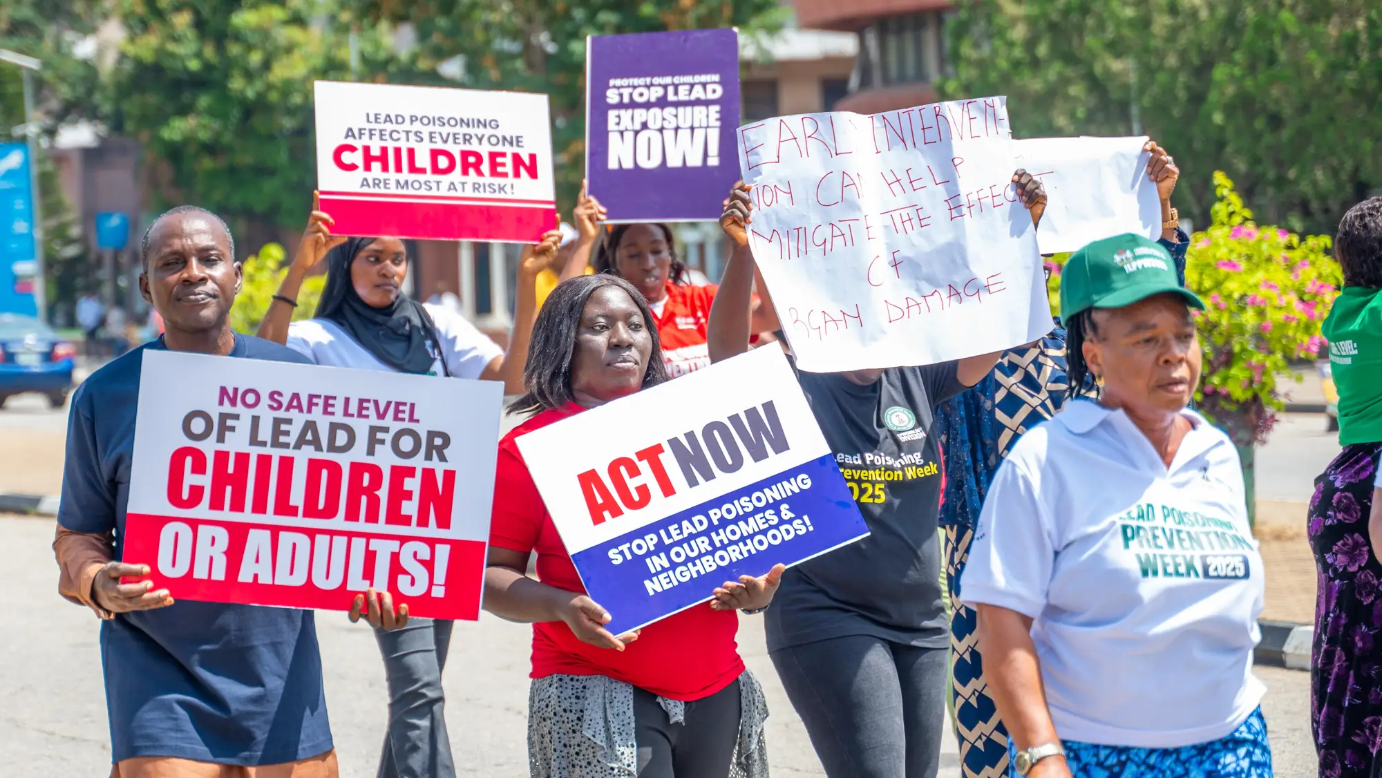 A group of Nigerian men and women marching and holding up protest signs that say 'Act Now!'